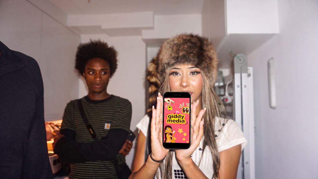 Guest in a fur hat holding the Giddy screen